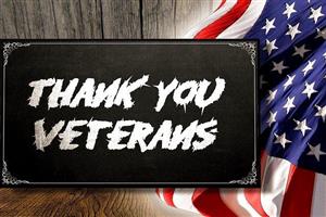 Thank you Veterans on a chalkboard sign in front of barn boards and an American flag